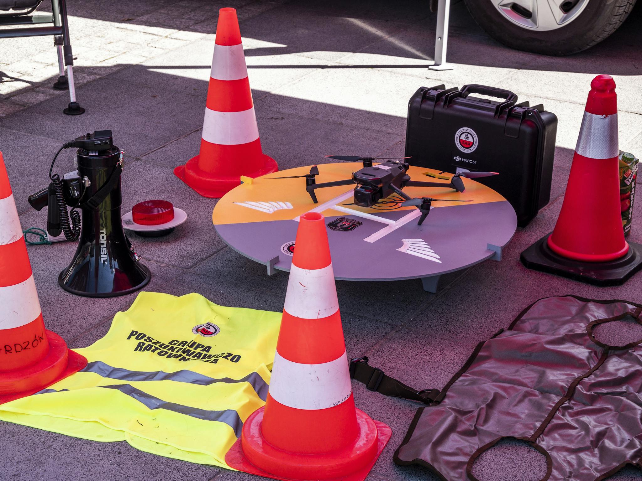 Drone, safety vests, and traffic cones at a construction site, showcasing modern safety and management tools.