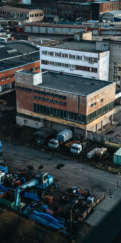 A detailed aerial view of an industrial site with buildings, trucks, and machinery under daylight.