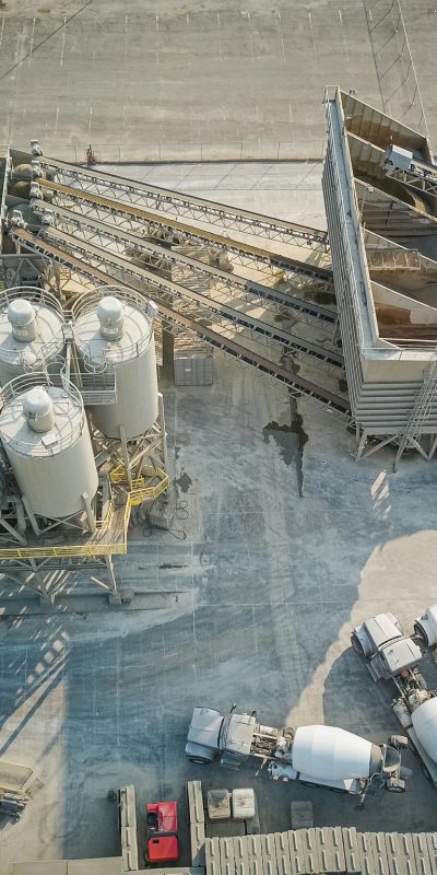 A drone-captured aerial view of an industrial concrete mixing plant with trucks and machinery.
