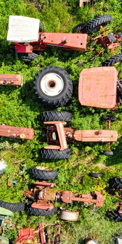 Drone captures a striking overhead view of a tractor junkyard in Misha Mokwa, WI showcasing rusted machinery and lush greenery.
