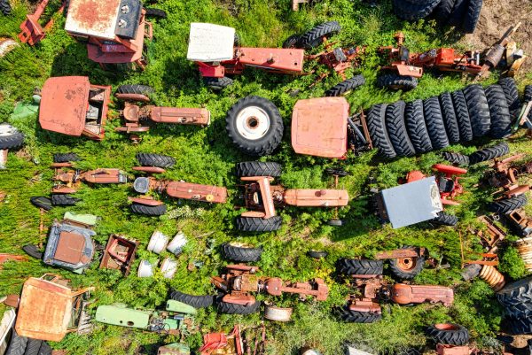 Drone captures a striking overhead view of a tractor junkyard in Misha Mokwa, WI showcasing rusted machinery and lush greenery.